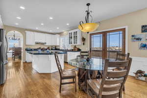 Dining room featuring light wood-style flooring, arched walkways, a wealth of natural light, and french doors