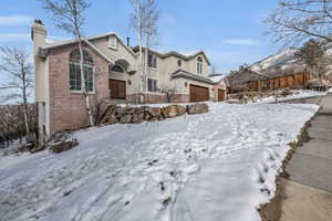 View of front of home featuring stucco siding, a chimney, fence, and brick siding