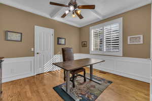 Office with crown molding, light wood-type flooring, a wainscoted wall, and beamed ceiling