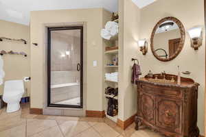 Full bathroom with toilet, a stall shower, tile patterned flooring, and built in shelves