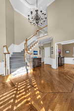 Unfurnished living room featuring arched walkways, a notable chandelier, stairway, ornamental molding, and wood finished floors