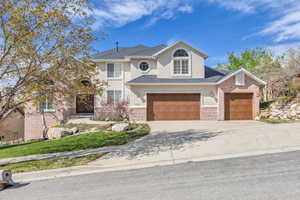 Traditional-style house featuring stucco siding, brick siding, concrete driveway, and a garage