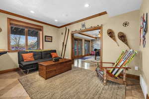 Living room featuring a textured ceiling, ornamental molding, and baseboards