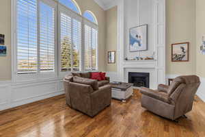 Living area with a fireplace, plenty of natural light, visible vents, and wood finished floors