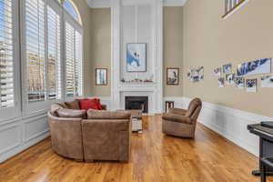 Living area with light wood finished floors, a fireplace, a high ceiling, and a wealth of natural light