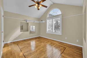 Spare room featuring vaulted ceiling with beams, ceiling fan, baseboards, and wood finished floors