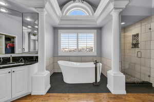 Full bath featuring decorative columns, tile walls, and a shower stall