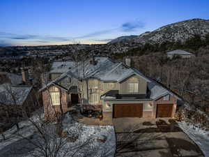 View of front of house featuring concrete driveway, brick siding, a mountain view, and stucco siding