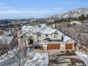 View of front facade featuring a mountain view, a garage, driveway, stucco siding, and a chimney