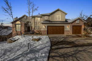 Traditional-style house featuring driveway, brick siding, a chimney, and stucco siding