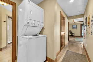 Laundry area featuring light tile patterned floors, baseboards, laundry area, and stacked washer / drying machine