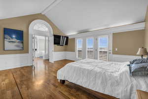 Bedroom featuring vaulted ceiling with beams, a wainscoted wall, access to outside, and wood finished floors