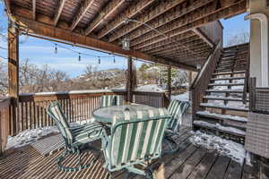 Snow covered deck featuring outdoor dining space, a mountain view, and stairway