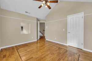 Unfurnished room with high vaulted ceiling, wood finished floors, visible vents, and baseboards