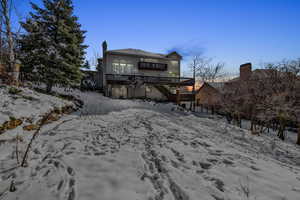 Snow covered property with stairway, a chimney, and a wooden deck