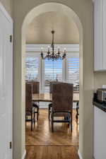 Dining space featuring arched walkways, wood finished floors, and a notable chandelier