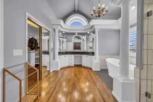 Bathroom featuring a freestanding tub, vaulted ceiling, vanity, and ornate columns