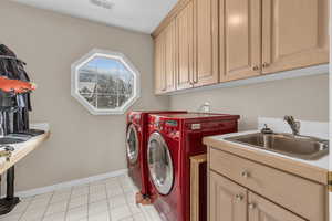 Laundry room featuring light tile patterned floors, washing machine and dryer, a sink, visible vents, and cabinet space