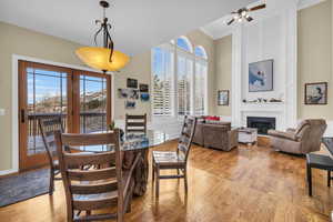 Dining room with a large fireplace, ornamental molding, a high ceiling, light wood-type flooring, and a decorative wall