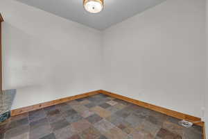 Unfurnished room with stone tile floors and baseboards