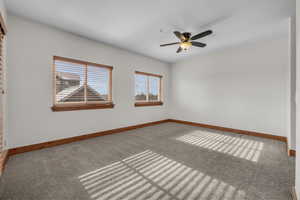 Carpeted empty room with ceiling fan and baseboards