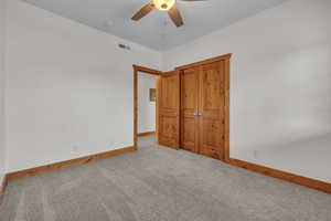 Unfurnished bedroom featuring a ceiling fan, light colored carpet, visible vents, and baseboards