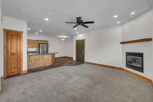 Unfurnished living room featuring recessed lighting, dark carpet, baseboards, and a glass covered fireplace