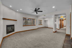 Unfurnished living room featuring a glass covered fireplace, visible vents, baseboards, and recessed lighting