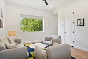 Living room featuring baseboards, wood finished floors, a ceiling fan, and recessed lighting
