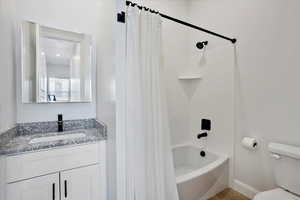 Full bath featuring toilet, shower / tub combo, baseboards, and vanity