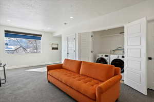 Living room featuring dark carpet, a textured ceiling, and baseboards