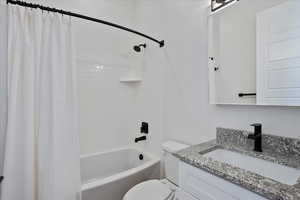 Full bathroom with shower / bathtub combination with curtain, toilet, and vanity