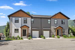 View of front of home featuring an attached garage, stone siding, and concrete driveway
