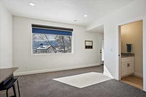 Unfurnished bedroom with a textured ceiling, dark colored carpet, recessed lighting, and baseboards