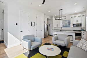 Living room featuring a notable chandelier, light wood finished floors, recessed lighting, visible vents, and baseboards