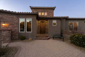 Doorway to property with stone siding, a patio area, and stucco siding