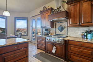 Kitchen with a healthy amount of sunlight, decorative light fixtures, stainless steel gas stovetop, and stone tile floors