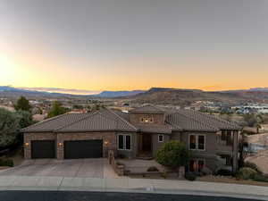 View of front of property featuring driveway, a tile roof, an attached garage, a mountain view, and stucco siding