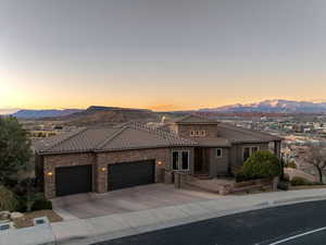 Mediterranean / spanish house featuring a garage, a tile roof, a mountain view, and concrete driveway