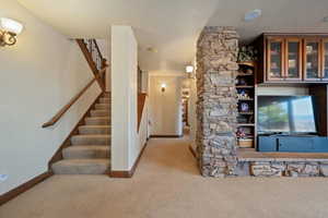 Interior space featuring light carpet, a textured ceiling, baseboards, and stairs