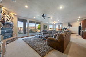 Living area with light carpet, a textured ceiling, a fireplace, and plenty of natural light