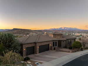 Mediterranean / spanish home featuring a garage, driveway, a tiled roof, a mountain view, and stucco siding