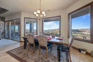 Dining space featuring a healthy amount of sunlight, stone tile floors, a mountain view, and a notable chandelier