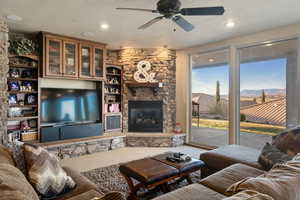 Living room featuring a ceiling fan, a fireplace, and a textured ceiling