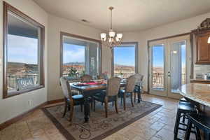 Dining area with stone tile floors, visible vents, baseboards, french doors, and a notable chandelier