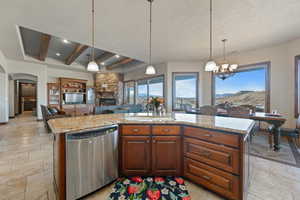 Kitchen with open floor plan, hanging light fixtures, stainless steel dishwasher, and a center island