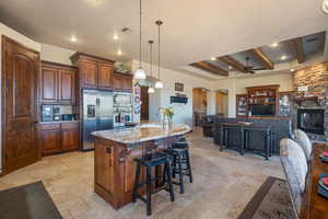 Kitchen featuring appliances with stainless steel finishes, a breakfast bar, open floor plan, hanging light fixtures, and a large island with sink