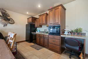 Kitchen featuring light stone counters, recessed lighting, light tile patterned flooring, a sink, and black appliances