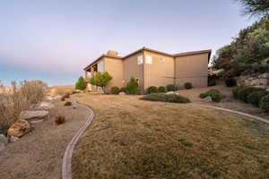 Property exterior at dusk featuring a lawn and stucco siding