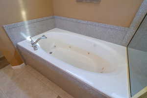 Full bath with a tub with jets and tile patterned floors